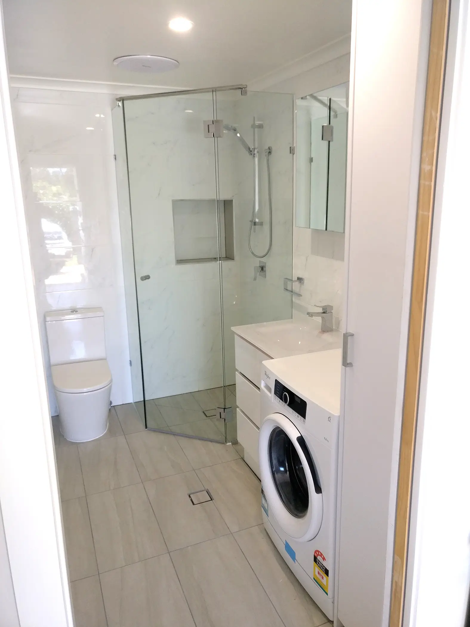 Finished bathroom in the converted sleepout, with glass shower and tiling